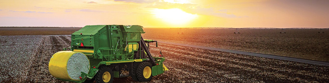 John Deere CP770 Cotton Picker with huge bale of cotton mounted behind it harvesting at susnet