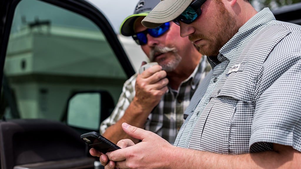 Two men looking at a phone in the field