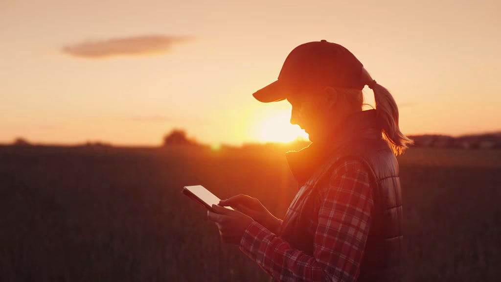 Close-up view of a farmer checking out Operations Center on her mobile device, thanks to her JDLink connectivity, which comes standard on C770 Series Cotton Harvesters.
