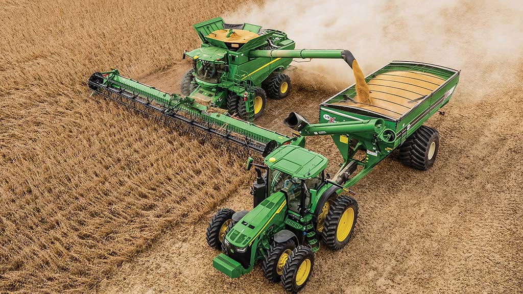 Combine emptying grain into grain cart in wheat field