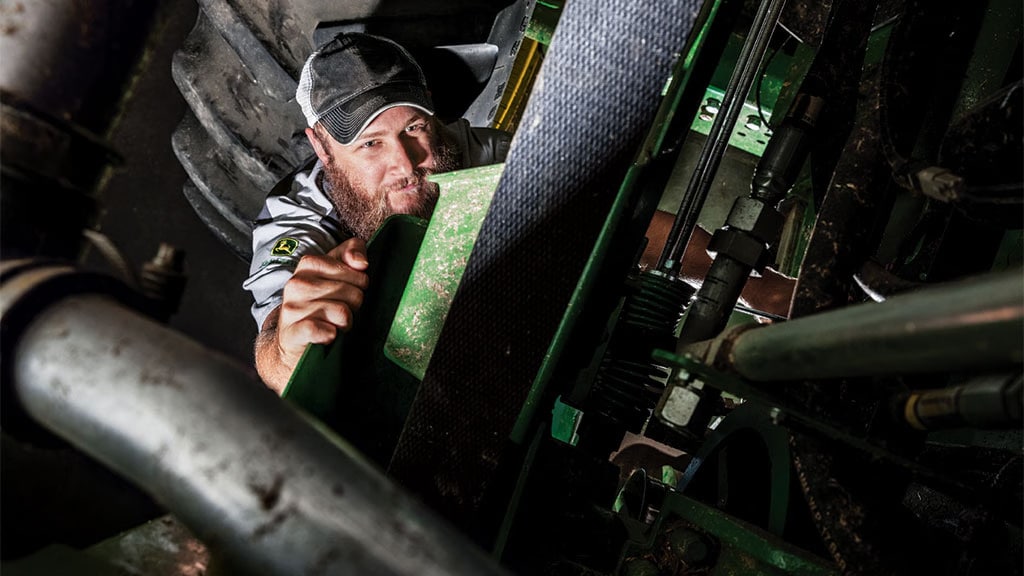 Photo showing a John&nbsp;Deere specialist inspecting a CH Series Sugar Harvester.