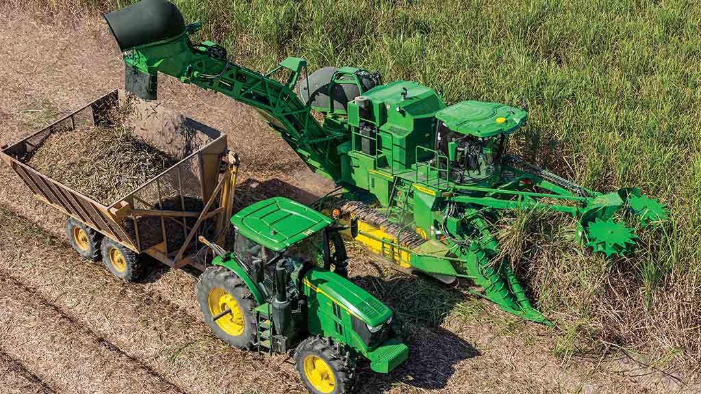 Overhead photo showing a CH Series Sugar Harvester unload crop into a tractor-pulled grain cart.