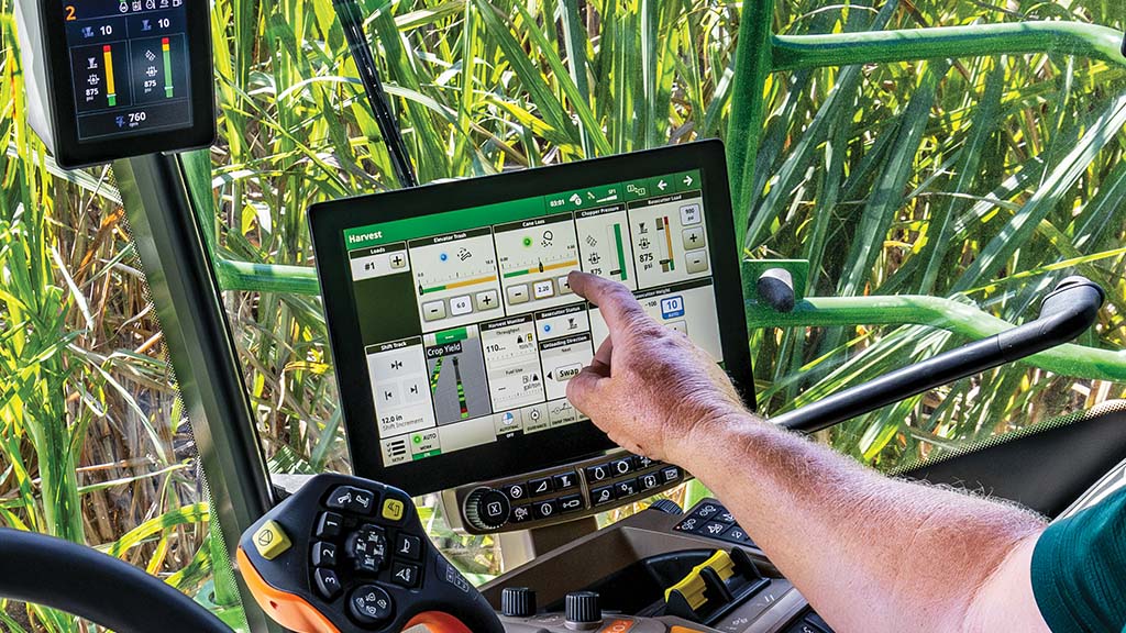 In-cab, close-up photo showing a farmer's arm and hand interacting with the G5 Display in a CH Series Sugar Harvesters.