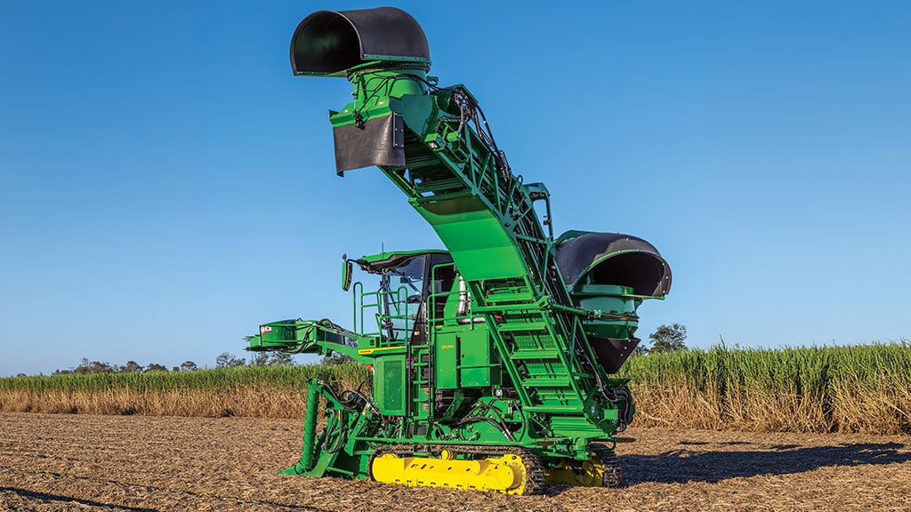 Rear-view photo showing a CH Series Sugar Harvester with elevated elevator in a sugar cane field.