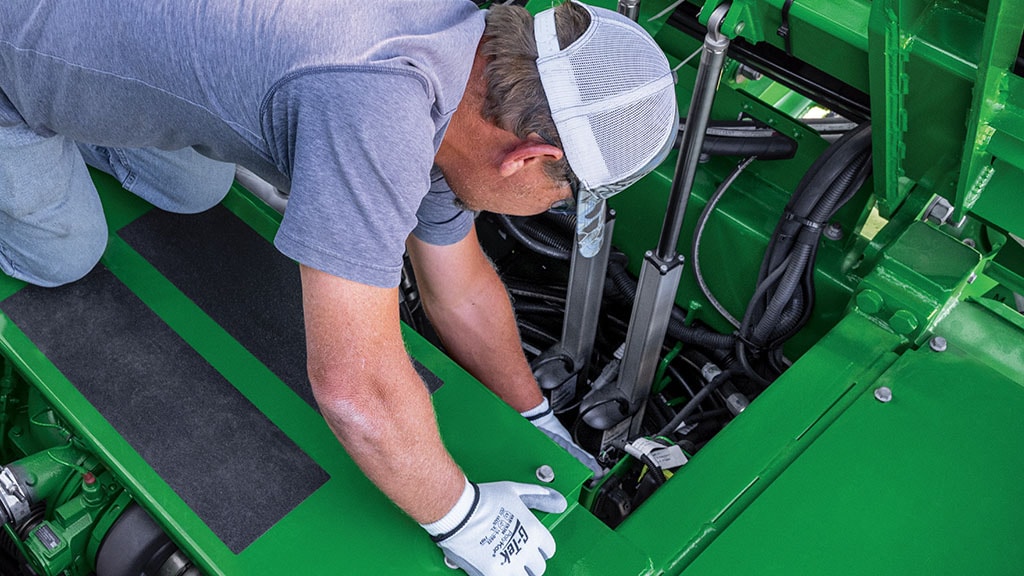 Close-up photo showing a farmer accessing the engine in a CH Series Sugar Harvester.