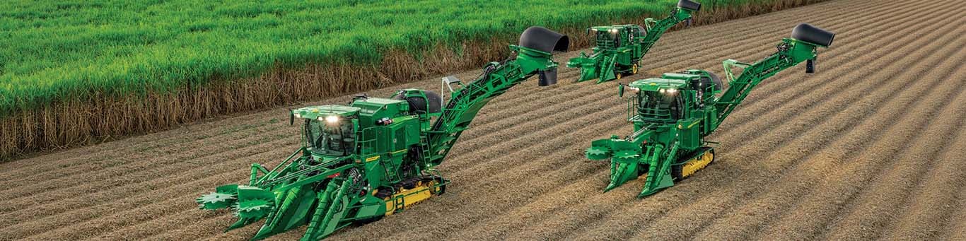 Wide-angle photo showing three CH Series Sugar Cane Harvesters operating in a partially harvested sugar cane field.