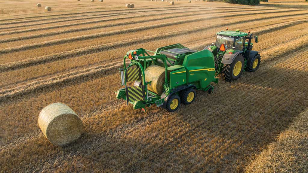 A baler in a field creating 4 foot by 5 foot bales.