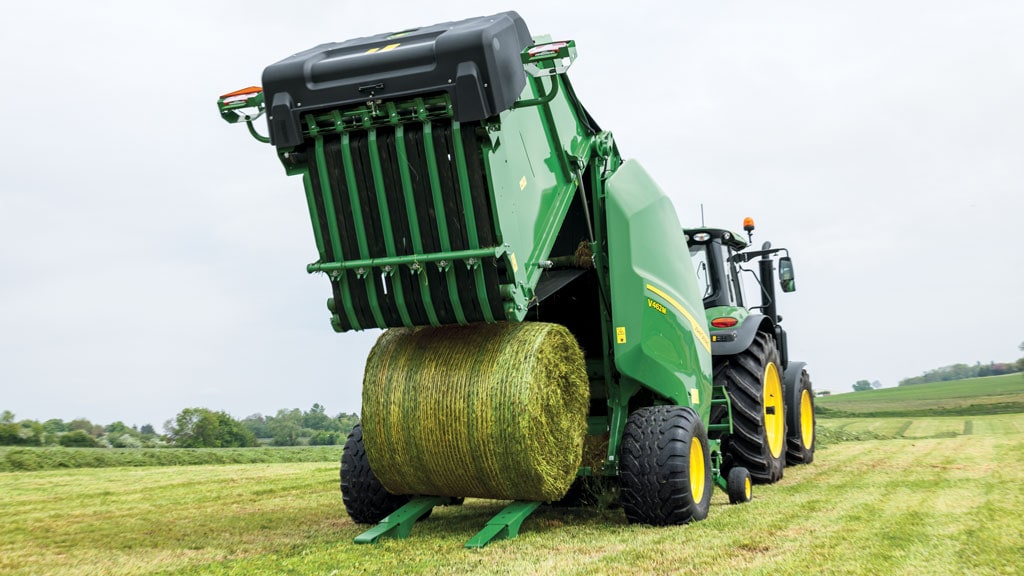 A baler over a field ejecting a hay bale