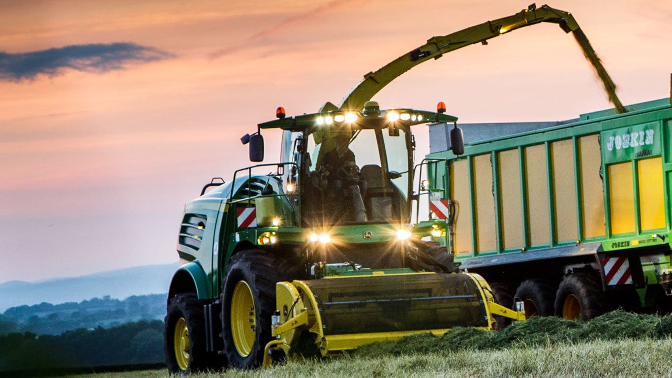 639 picking up hay in a field and dumping it into a bin