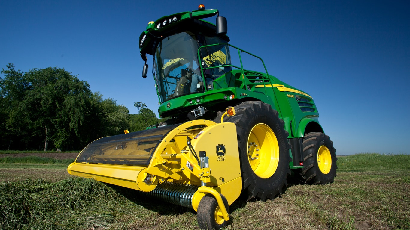 649 picking up hay in a field and dumping it into a bin