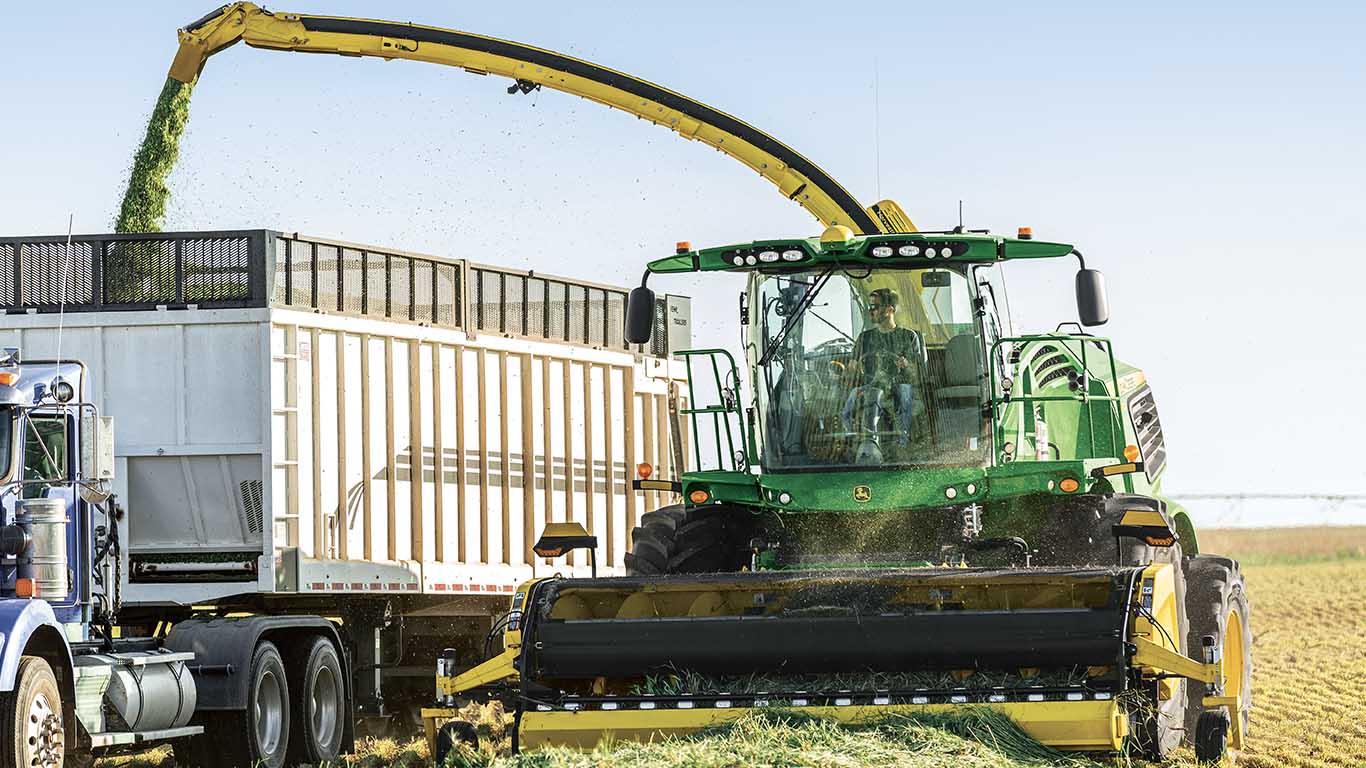 46R picking up hay in a field and dumping it into a bin