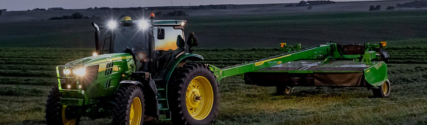 evening view of tractor with a mower-conditioner attached working in field