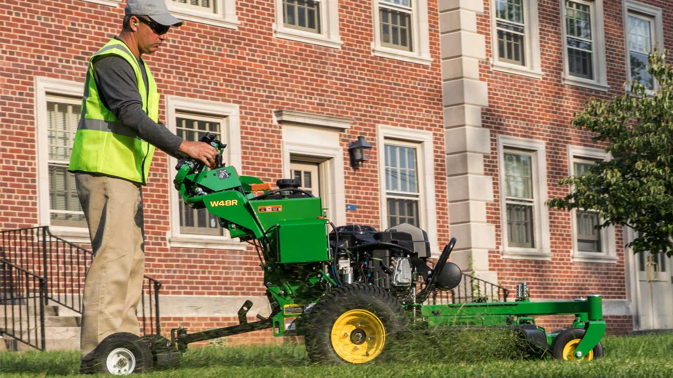 Guy on sulki with walk behind mower