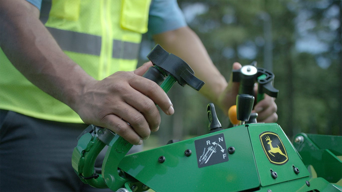 Moving gif image showing hands pushing levers on a walk behind mower