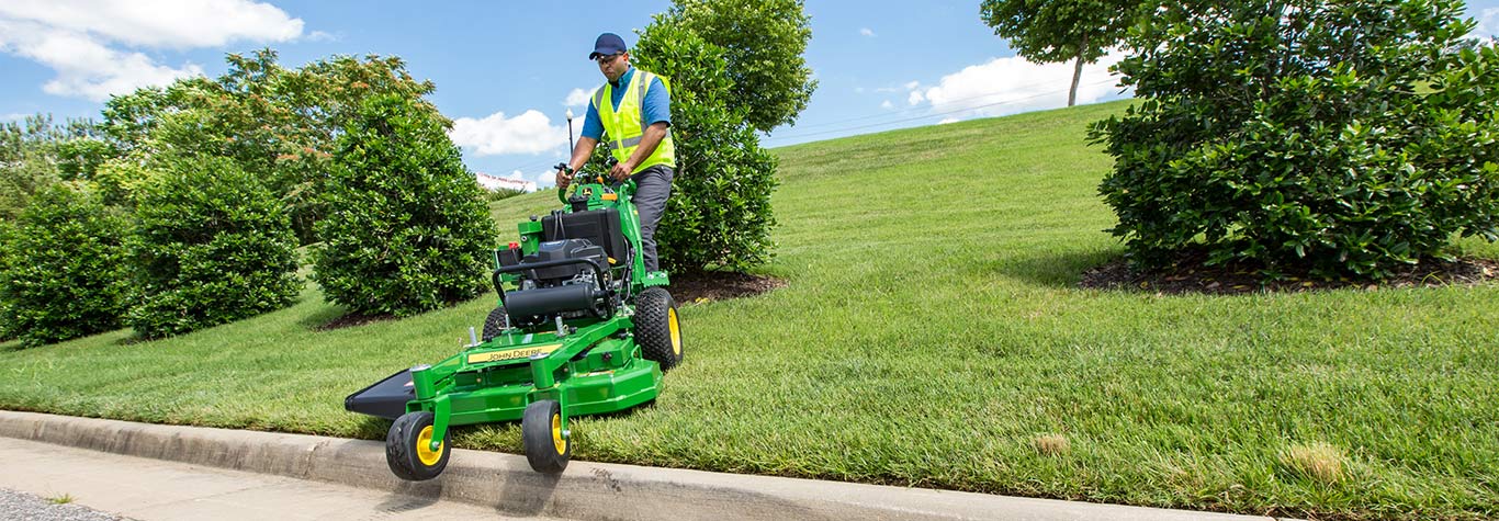 man going over curb with walk behind mower