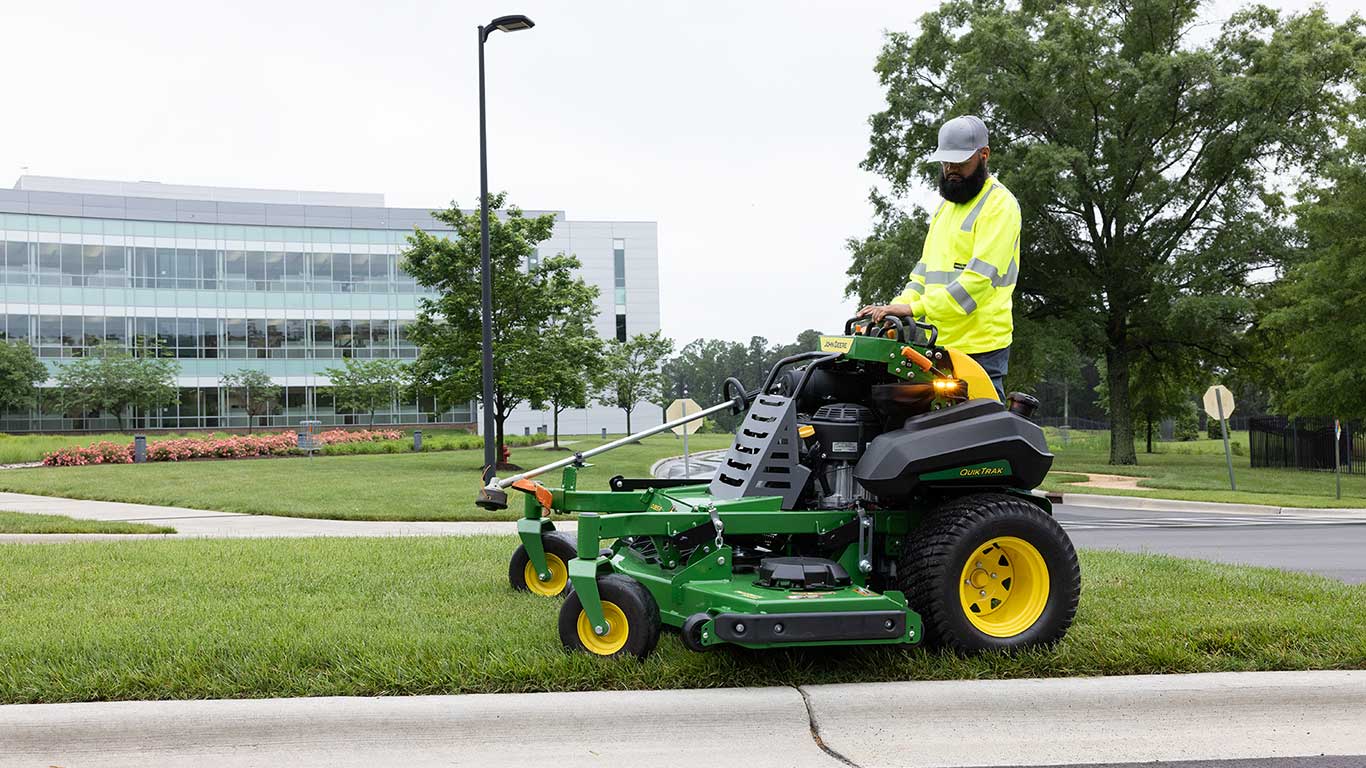 Person standing on quiktrak mower mowing the lawn