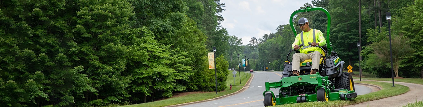 man riding a ztrak mower along the edge of a road