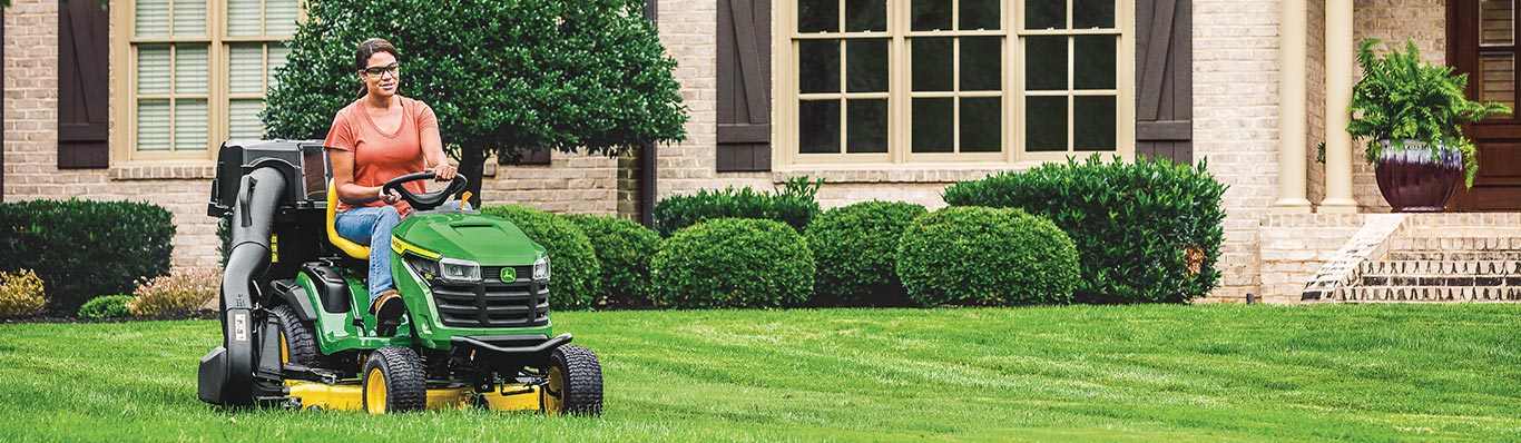 woman driving 100 series lawn tractor in yard