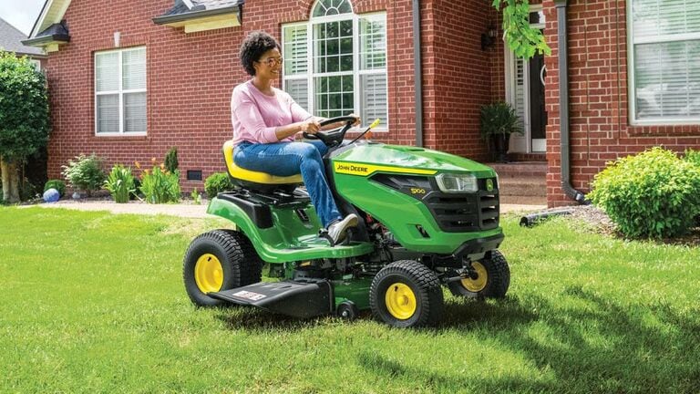 Person riding on a S100 mower near a house