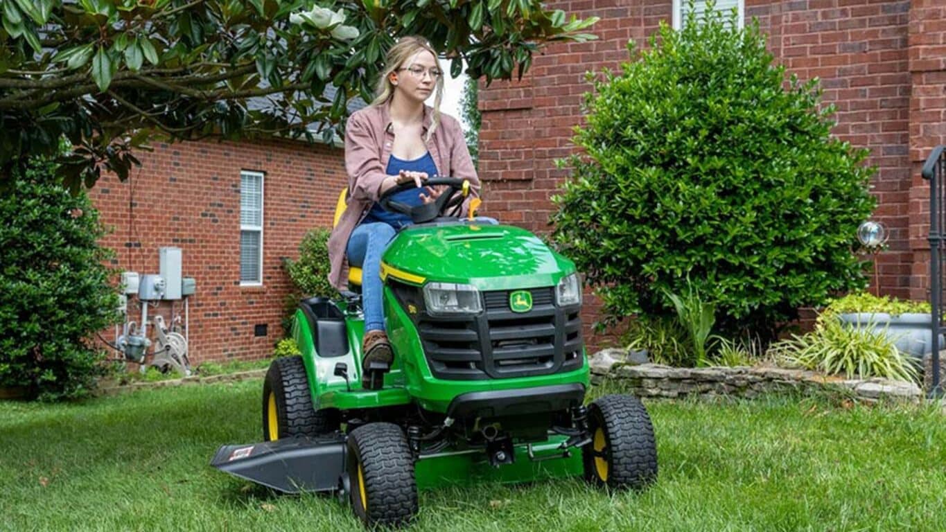 Person riding on a S110 mower in front of a home