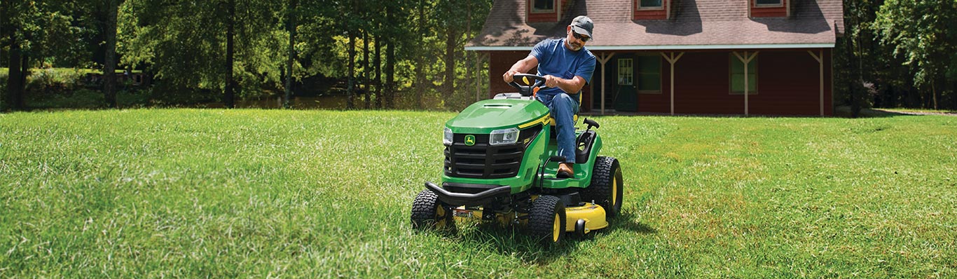 man driving 200 series lawn tractor in yard