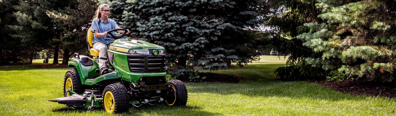 Woman riding X739 Series Lawn Tractor mowing a yard