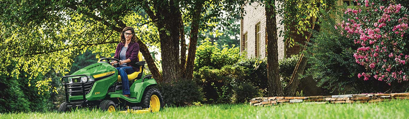 woman driving X500 lawn tractor in yard