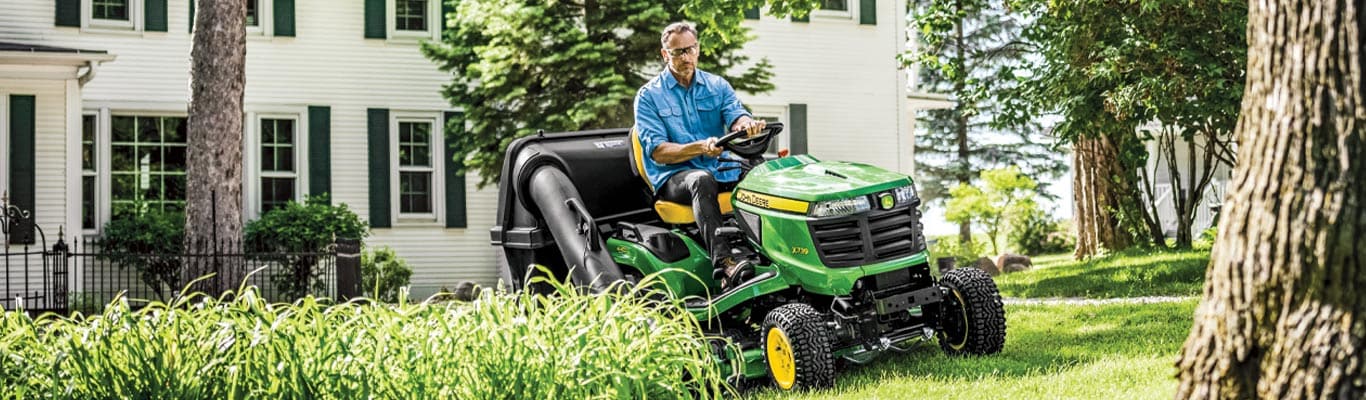 Man in blue denim shirt driving a X700 lawn tractor