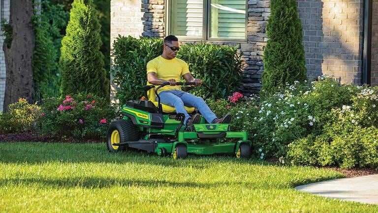Person riding a Z330R mower in front of a house