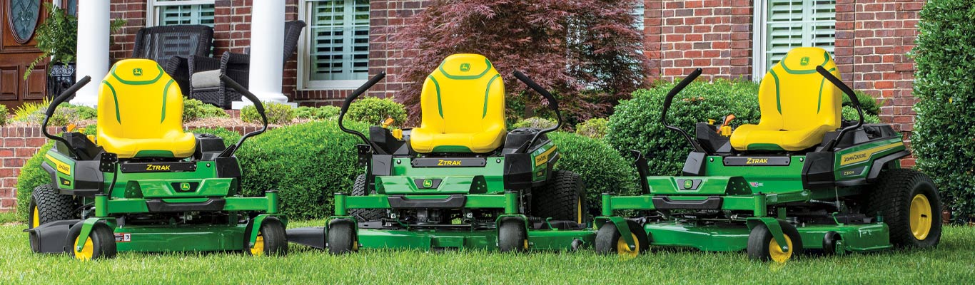 Photo lineup of zero-turn mowers in front of house
