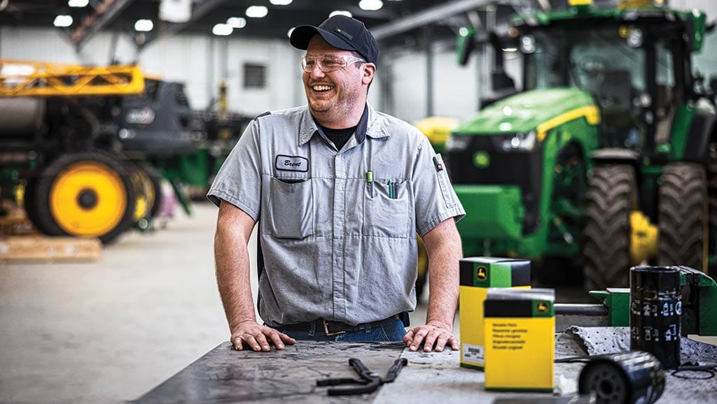 John Deere service technician with tractor in background
