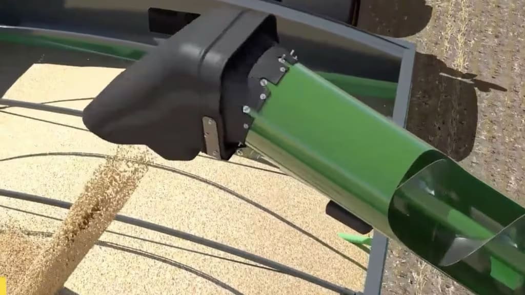 Close-up of agricultural machinery unloading grain, showing a green chute dispensing grains onto a sandy surface.