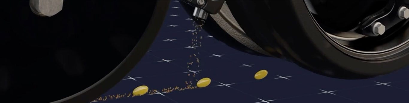 A close-up of a robotic arm dispensing yellow capsules onto a dark grid-like surface, scattering particles as it moves.