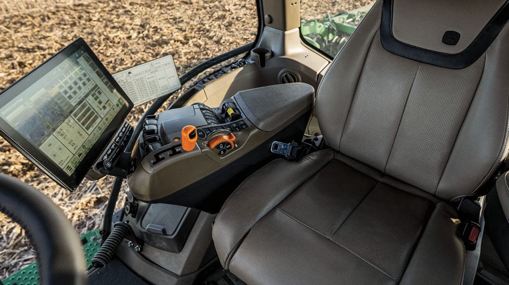 Tractor cab interior with operator seat and touchscreen display.