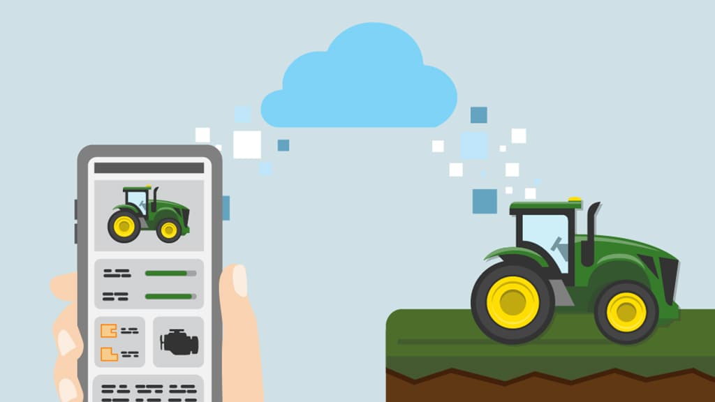 someone holding a cell phone and data uploading into a tractor
