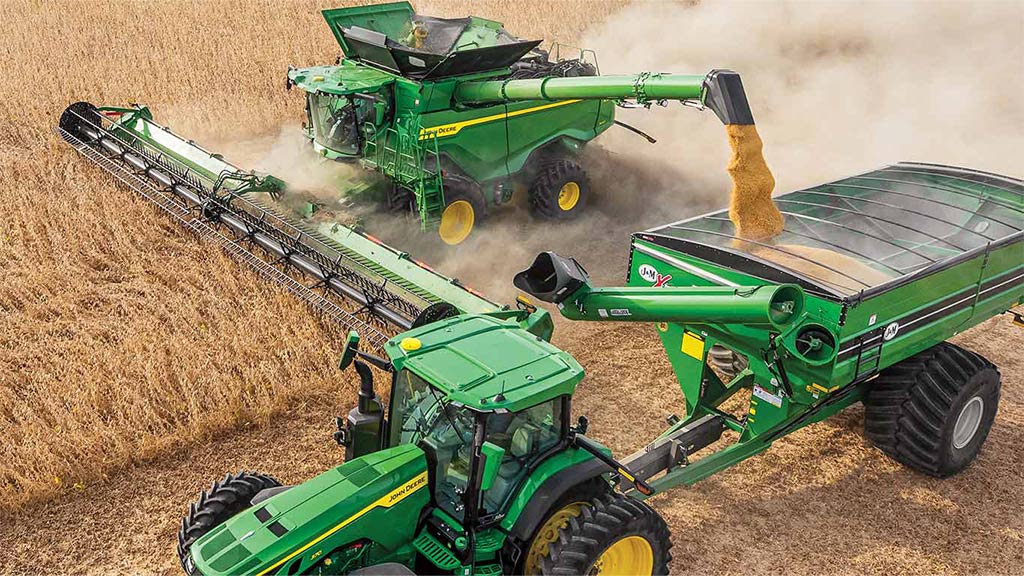 Image of a Combine using Machine Sync in a corn field emptying grain in a cart pulled by a tractor.