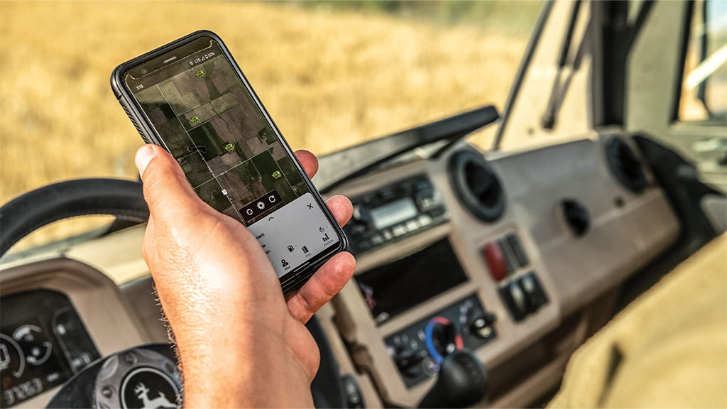 Image of person holding cell phone with Operations Center on screen, sitting in their truck in the field.