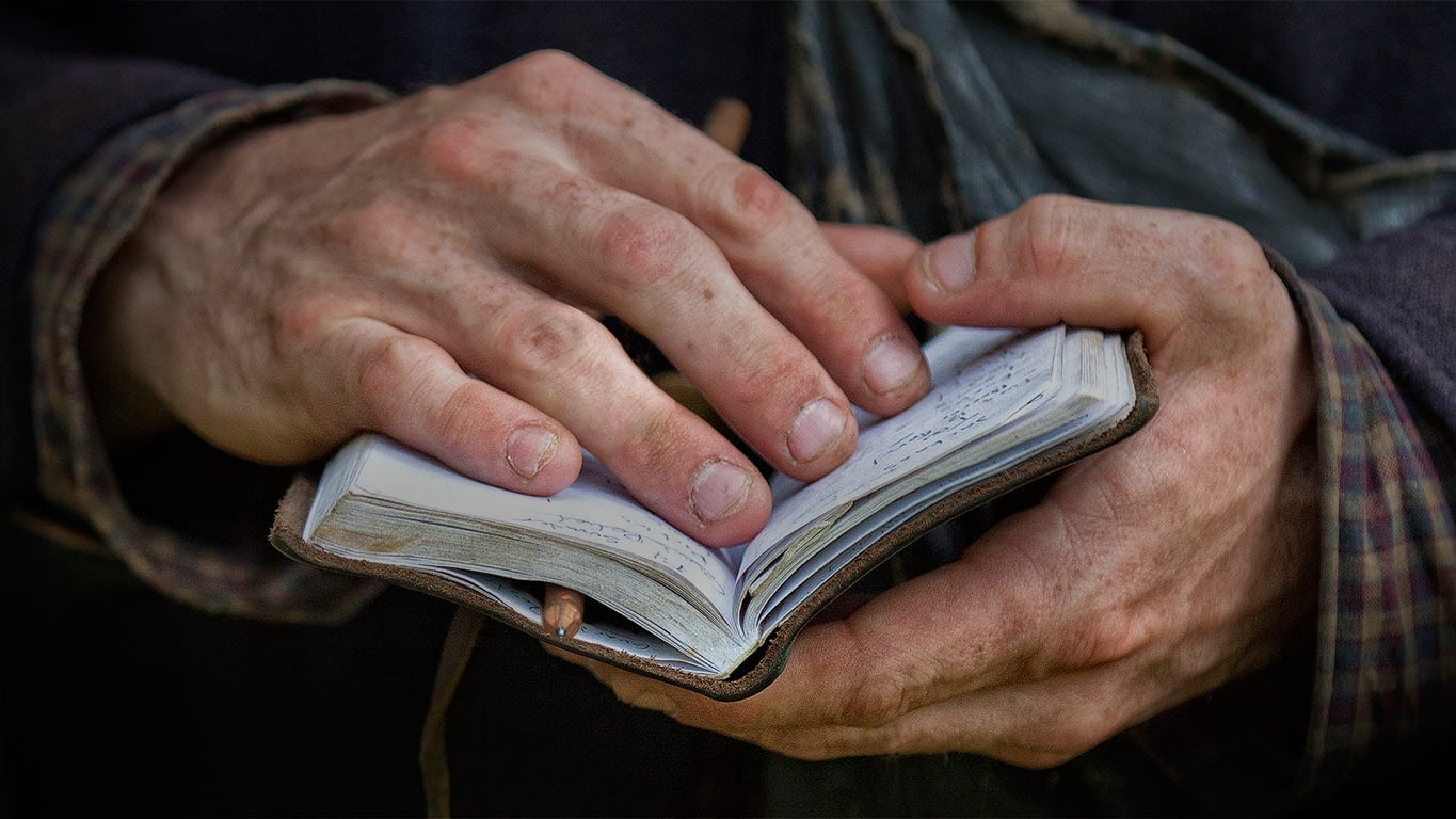 Close up of hands holding a small notebook open.