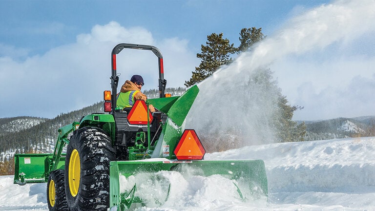 person operating a 4052m removing snow with a rear snowblower attachment