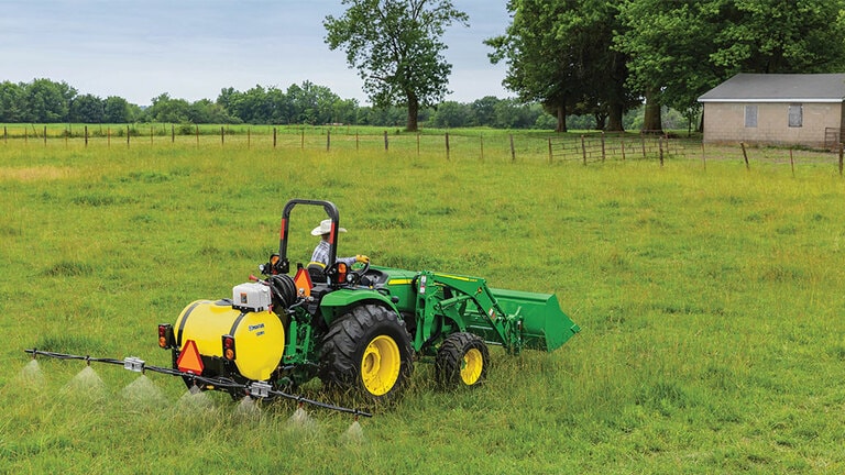 person operating a 4066m in a field with a rear sprayer attachment