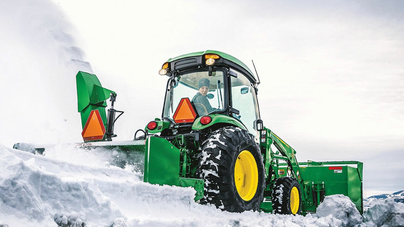 person operating a 4066r removing snow with a rear snowblower attachment