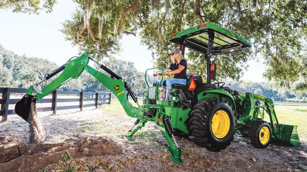 Person operating a 3025E tractor with a 370B backhoe attachment.