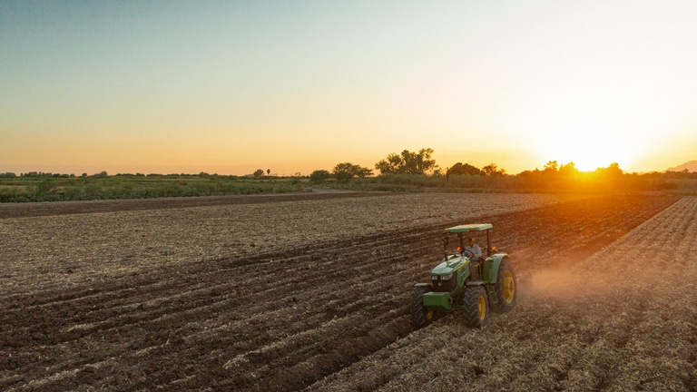 Tractor John Deere en el campo al atardecer