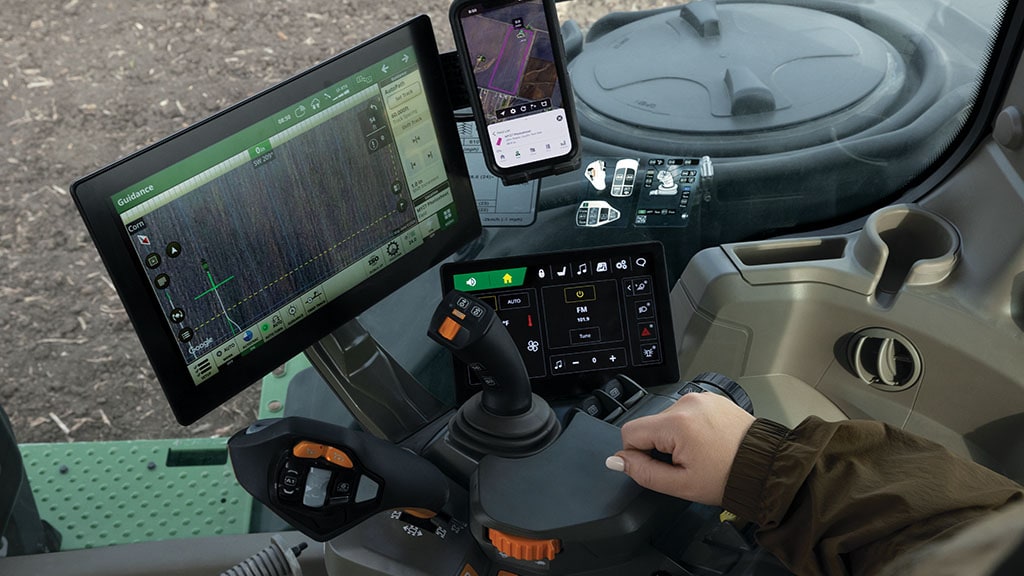 View of inside the cab of a John Deere 8 Series Tractor with Convenience Display, wireless phone charger, and CommandX™ transmission controls