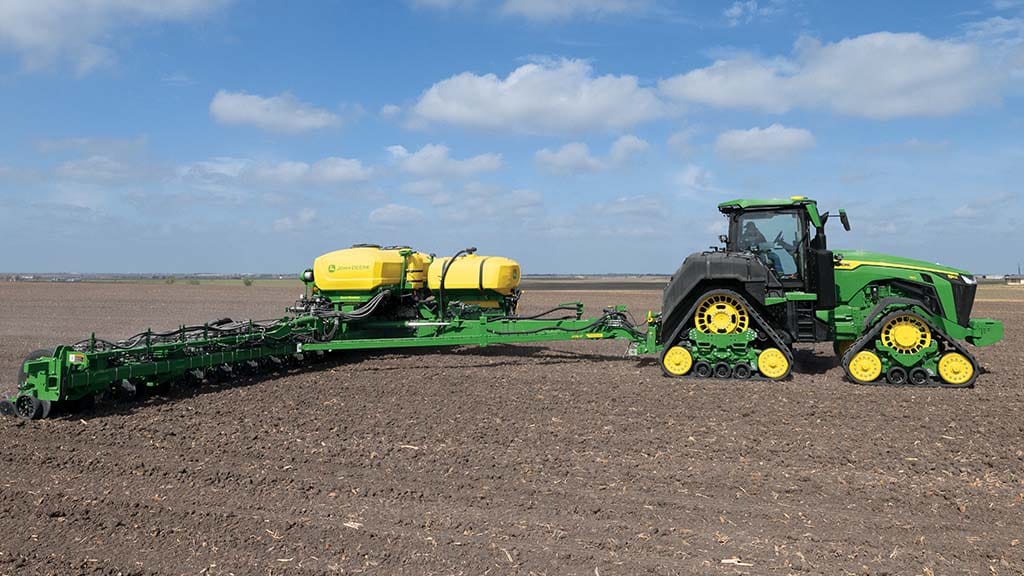 A green tractor on a field with a blue sky above.