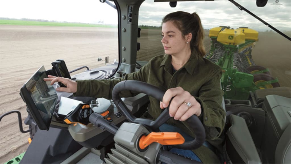 Operator pressing a button on a touchscreen display in the cab of a high-horsepower 8 Series Tractor while planting in a field.