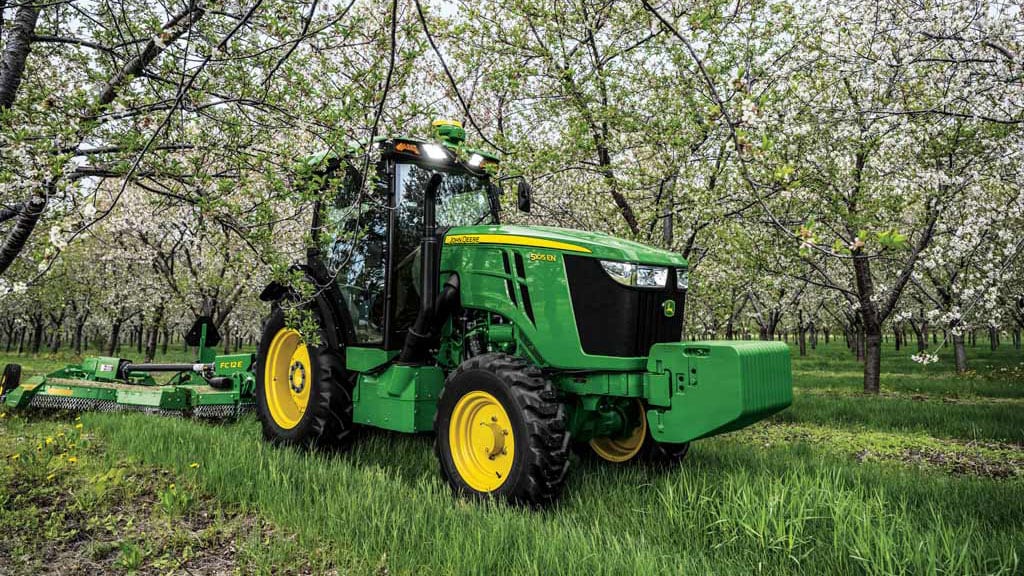 John Deere tractor hauling attachment through grass