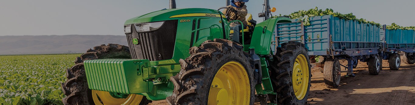 john deere tractor pulling carts in a field