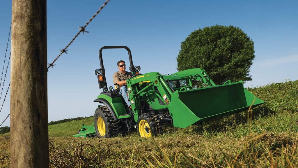 2r series tractor with a loader and mower attached driving by wire fence