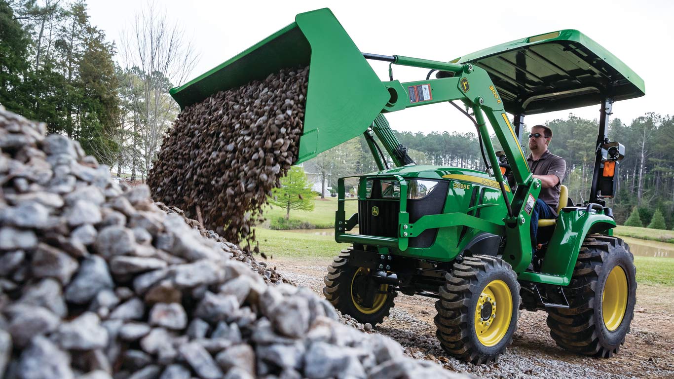 image of 3025e compact utility tractor dumping rocks
